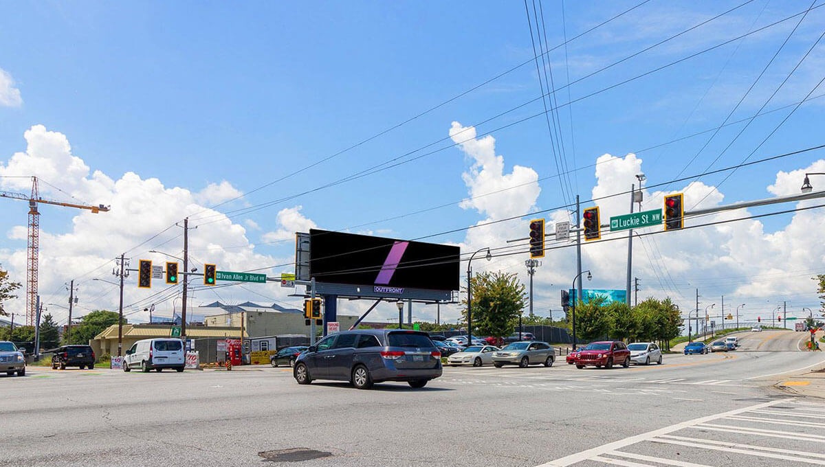 Urban street scene in Atlanta with vehicles, traffic signals, and a prominent digital billboard on Ivan Allen Jr Blvd.