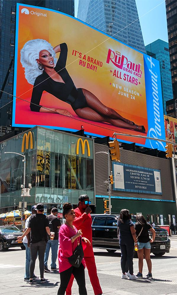Times Square advertisement for 'RuPaul's Drag Race All Stars' season premiere, set against the backdrop of a busy New York street.