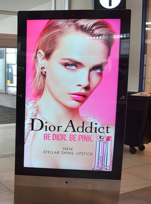 Digital display showing a Dior Addict advertisement for Stellar Shine Lipstick with the tagline 'Be Dior. Be Pink.