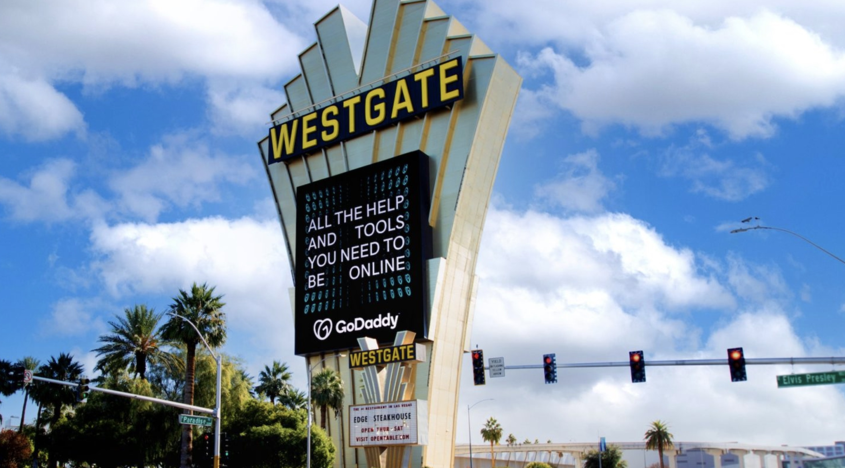 vegas-billboard Westgate Las Vegas sign displaying a GoDaddy ad with the message, 'All the help and tools you need to be online,' against a backdrop of palm trees and a blue sky