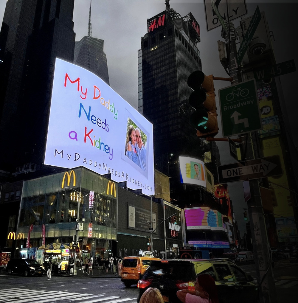 Large Times Square ad featuring a personal appeal for a kidney donation, including a family picture and the URL 'MyDaddyNeedsAKidney.com.