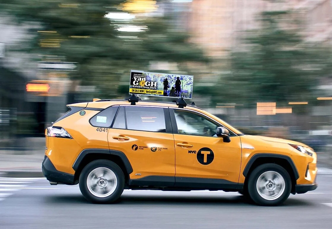 Outdoor billboard located near a road with passing traffic